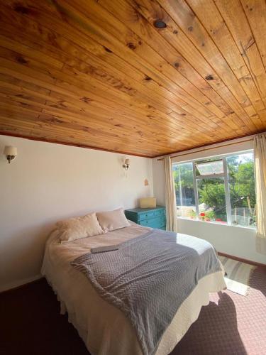 1 dormitorio con 1 cama con techo de madera en Exquisito Loft en Punta de lobos - Tranquilo y cómodo, en Pichilemu
