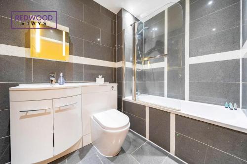 a bathroom with a toilet and a sink and a tub at QUALITY SERVICED APARTMENTS IN CAMBERLEY TOWN CENTRE, FREE WiFi, PERFECT FOR BUSINESS STAYS, FAMILIES, RELOCATIONS, EXTENDED STAYS, AND EMERGENCY ACCOMMODATION by REDWOOD STAYS in Camberley