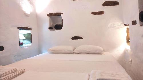 a white room with two pillows on a bed at Fyrou- Serenity / Idyllic Traditional Experience in Artemonas