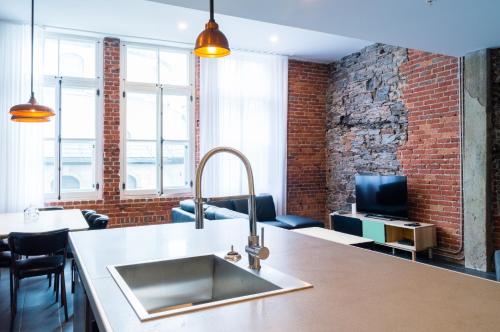 a kitchen with a sink and a brick wall at Les Lofts du Trésor - Par Les Lofts Vieux-Québec in Quebec City