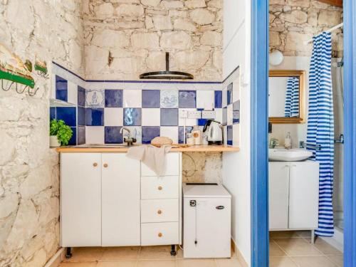a kitchen with white cabinets and blue and white tiles at Cornaro House in Arsos