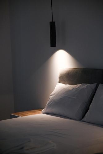 a bed with a white pillow and a light on the wall at Costa Varda Apartments in Mourteri