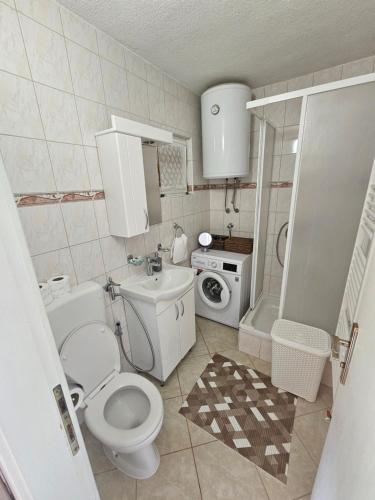 a bathroom with a toilet and a washing machine at Holiday House Bella in Bihać