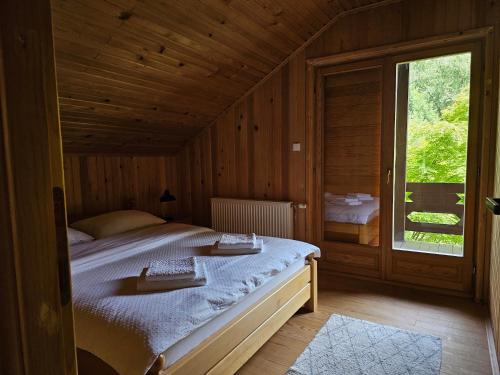 a large bed in a wooden room with a window at Holiday House Bella in Bihać