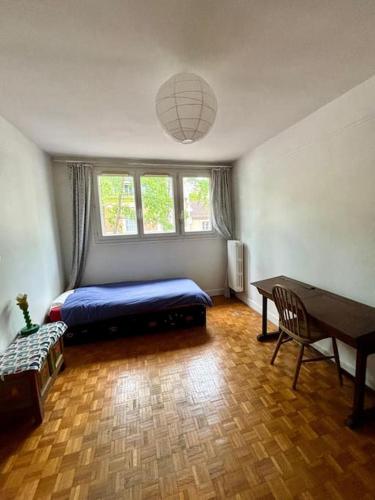une chambre avec un lit, une table et un bureau dans l'établissement Grand appartement familial, proche Stade de France, à Aubervilliers