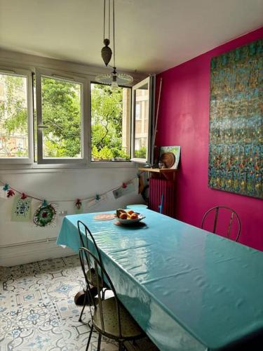une salle à manger avec une table bleue et des murs roses dans l'établissement Grand appartement familial, proche Stade de France, à Aubervilliers