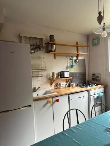 une cuisine avec des armoires blanches et un réfrigérateur blanc dans l'établissement Grand appartement familial, proche Stade de France, à Aubervilliers