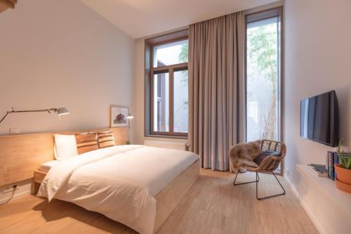 1 dormitorio con 1 cama, TV y silla en Great, en Gante
