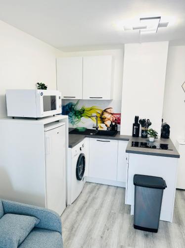 une cuisine avec des armoires blanches et un micro-ondes dans l'établissement Appartement T2 4 personnes RDC 50m plage et corniche, à Saint-Hilaire-de-Riez