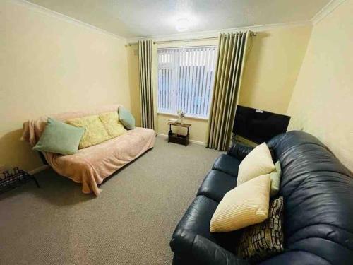 uma sala de estar com um sofá de couro e uma janela em Cosy 1st floor 2 bedroom flat em Little Paxton