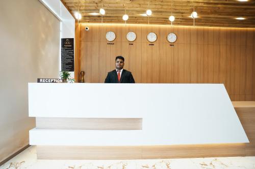a man in a suit standing behind a reception desk at Madhav Residency Hotel & Banquet, Kalyan, Mumbai in Kalyan