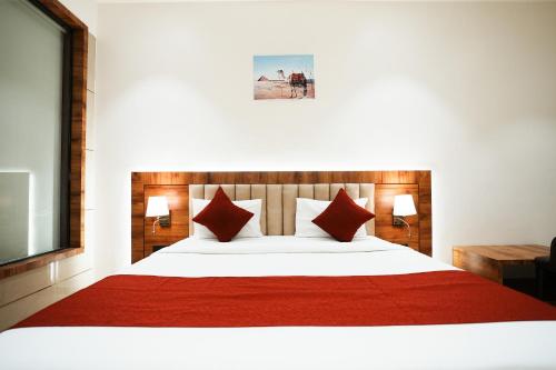 a bedroom with a large bed with red sheets and pillows at Madhav Residency Hotel & Banquet, Kalyan, Mumbai in Kalyan