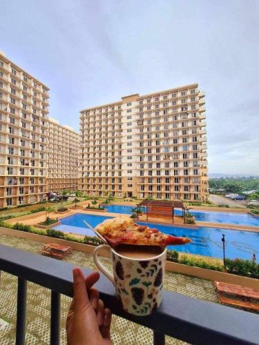 a person holding a plate of pizza and a cup of coffee at MaryneL Suites in Suba