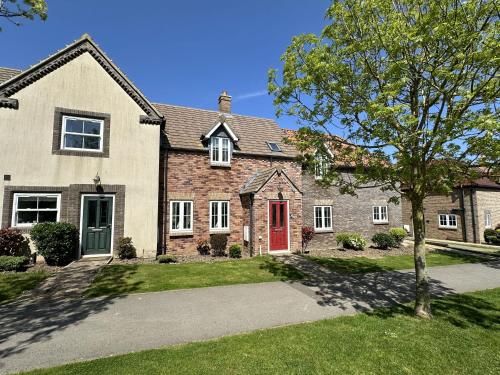 a large brick house with a red door at Lees Plaice - Part of the The Bay Filey Holiday Village with pool, gym and direct beach access, pub, restaurant, tennis and meadows walks in Filey