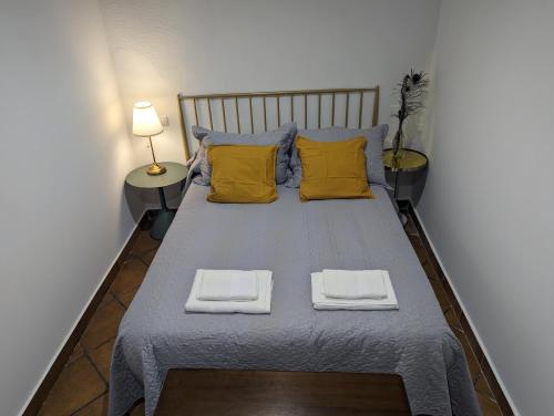 a large bed with two yellow pillows and two towels at Alojamiento 13 Jotas in Iniesta