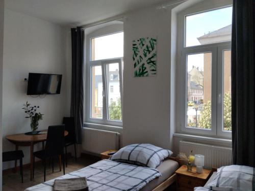 een slaapkamer met een bed en een tafel en ramen bij Pension Eberhart in Treuen
