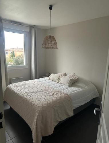 une chambre blanche avec un lit avec une fenêtre dans l'établissement Villa , calme et reposante, à Nîmes