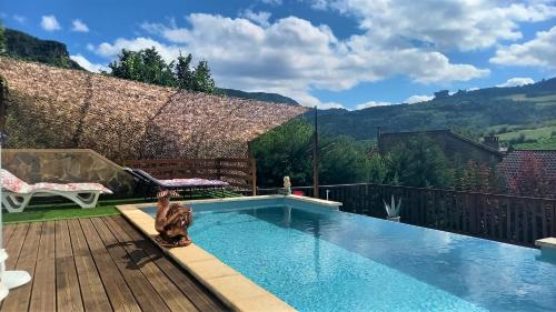un gato sentado en una terraza junto a una piscina en Les GARGOUILLES Gorges du Tarn - Millau, en Boyne