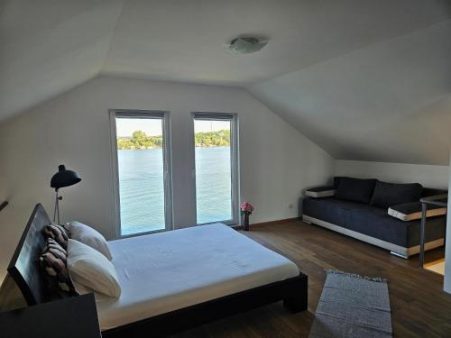 ein Schlafzimmer mit einem Bett, einem Sofa und Fenstern in der Unterkunft Kuca na reci Sunset Sava in Ostružnica