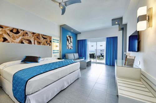a bedroom with a large bed and a living room at Riu Dunamar - All Inclusive in Cancún