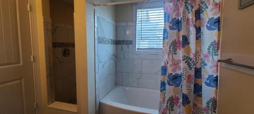 a bathroom with a tub and a shower curtain at Beach Road Bed and Breakfast in Kill Devil Hills