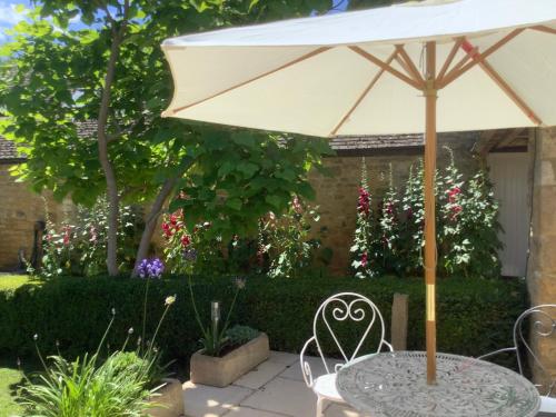 a table with an umbrella in a garden at Holly House in Ebrington