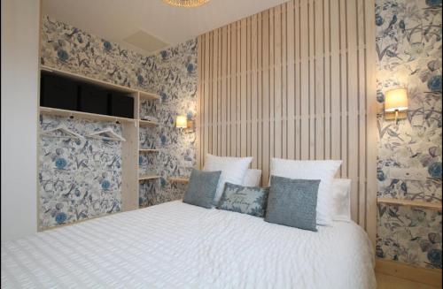 a bedroom with a bed with blue and white wallpaper at Face aux Isles in Saint-Marcouf