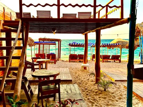 BARU MAGGYBEACH في بلايا بلانكا: شاطئ به كراسي وطاولات والمحيط