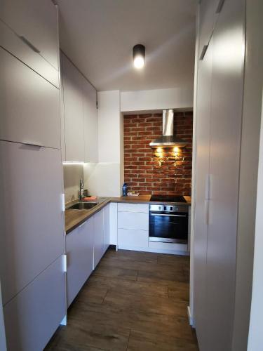 a kitchen with white cabinets and a brick wall at Apartament Siedlce in Siedlce
