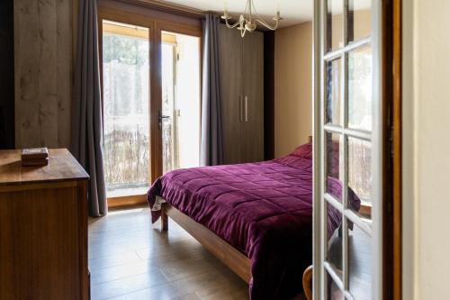 une chambre avec un lit violet et une fenêtre dans l'établissement Mas d'Hélène, charme en Provence, à Châteaurenard