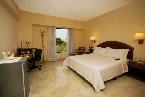a bedroom with a bed and a desk and a window at Fiesta Inn Colima in Colima