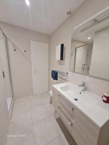 une salle de bain blanche avec un lavabo et un miroir dans l'établissement Notre cœur de ville douillet, à Sète