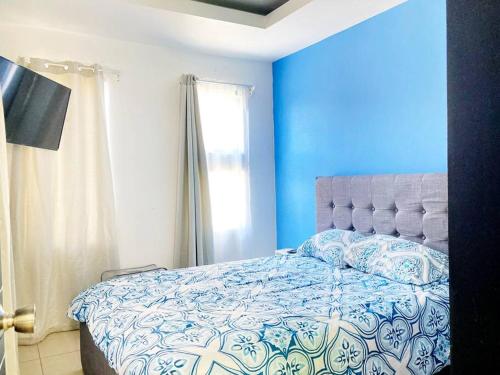 a blue bedroom with a bed and a window at Casa Matiza in Santiago Este