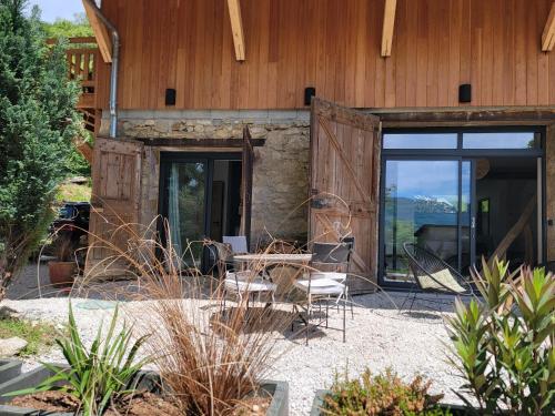 a patio with a table and chairs in front of a building at L'Alpage, vue lac in Brison-Saint-Innocent