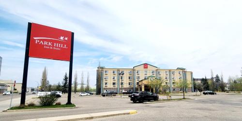 a parking lot with a red sign in front of a building at Park Hill Inn & Suite in Red Deer