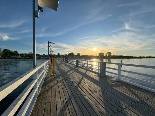 ein hölzerner Pier mit Sonnenuntergang auf dem Wasser in der Unterkunft Willa Morska Przystań w Pierwoszynie in Pierwoszyno