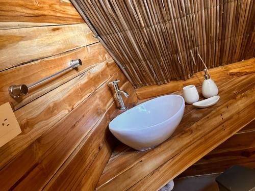 ein Badezimmer mit einem weißen Waschbecken in einer Holzwand in der Unterkunft BARU MAGGYBEACH in Playa Blanca