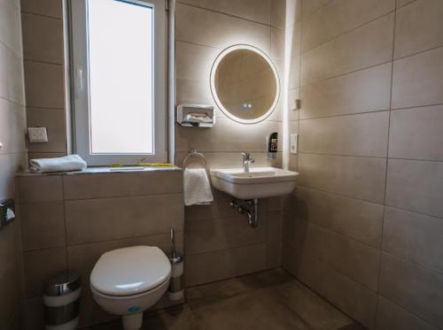 a bathroom with a toilet and a sink and a window at Mey Boardinghouse in Bielefeld