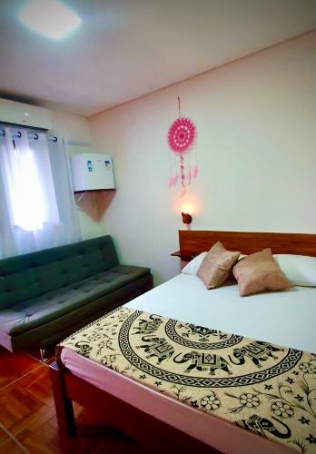 ein Schlafzimmer mit einem Bett und einem grünen Sofa in der Unterkunft Pousada Casa das Flores Camburi in Camburi