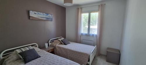 een kleine kamer met 2 bedden en een raam bij HOUSE CLOSE TO ROYAN AND SEASIDE, GROUND FLOOR, QUIET AND COMFORTABLE in Médis