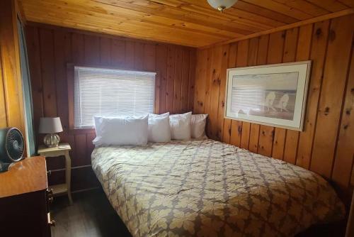 a bedroom with a bed in a wooden room at Lake Huron - 1 Bedroom, 1 Bath Lake Front Cabin (Sleeps 4) in Oscoda