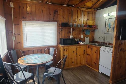 a kitchen with a table and a table and chairs at Lake Huron - 1 Bedroom, 1 Bath Lake Front Cabin (Sleeps 4) in Oscoda