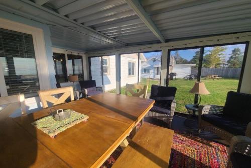 a screened in porch with a wooden table and chairs at Lake Huron - 3 Bedroom, 2 Bath Lake Front Home (Sleeps 12) in Oscoda