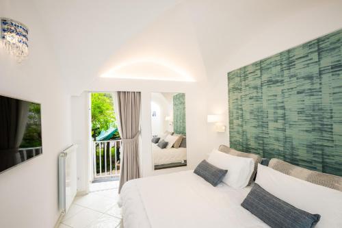 a bedroom with a white bed and a balcony at La Divina Amalfi Coast in Praiano