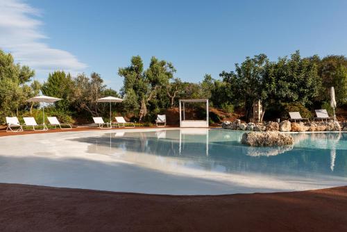 a swimming pool with chairs and a gazebo at Masseria Borgo San Marco in Fasano