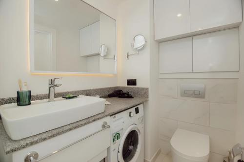 ein weißes Badezimmer mit einem Waschbecken und einer Waschmaschine in der Unterkunft Hotel in Orbi City Official in Batumi