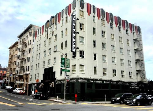 un gran edificio blanco en una calle de la ciudad con coches aparcados delante en EMBASSY HOTEL, en San Francisco