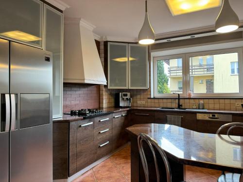 eine Küche mit einem Kühlschrank aus Edelstahl und einem Tisch in der Unterkunft Willa Morska Przystań w Pierwoszynie in Pierwoszyno