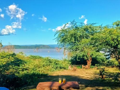 a view of a river with a tree and a table at Popo Camp Lake Baringo in Ol Kokwe