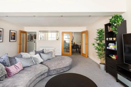 a living room with a couch and a tv at Beautiful 2 Bed Apartment just steps to the Beach in Weymouth
